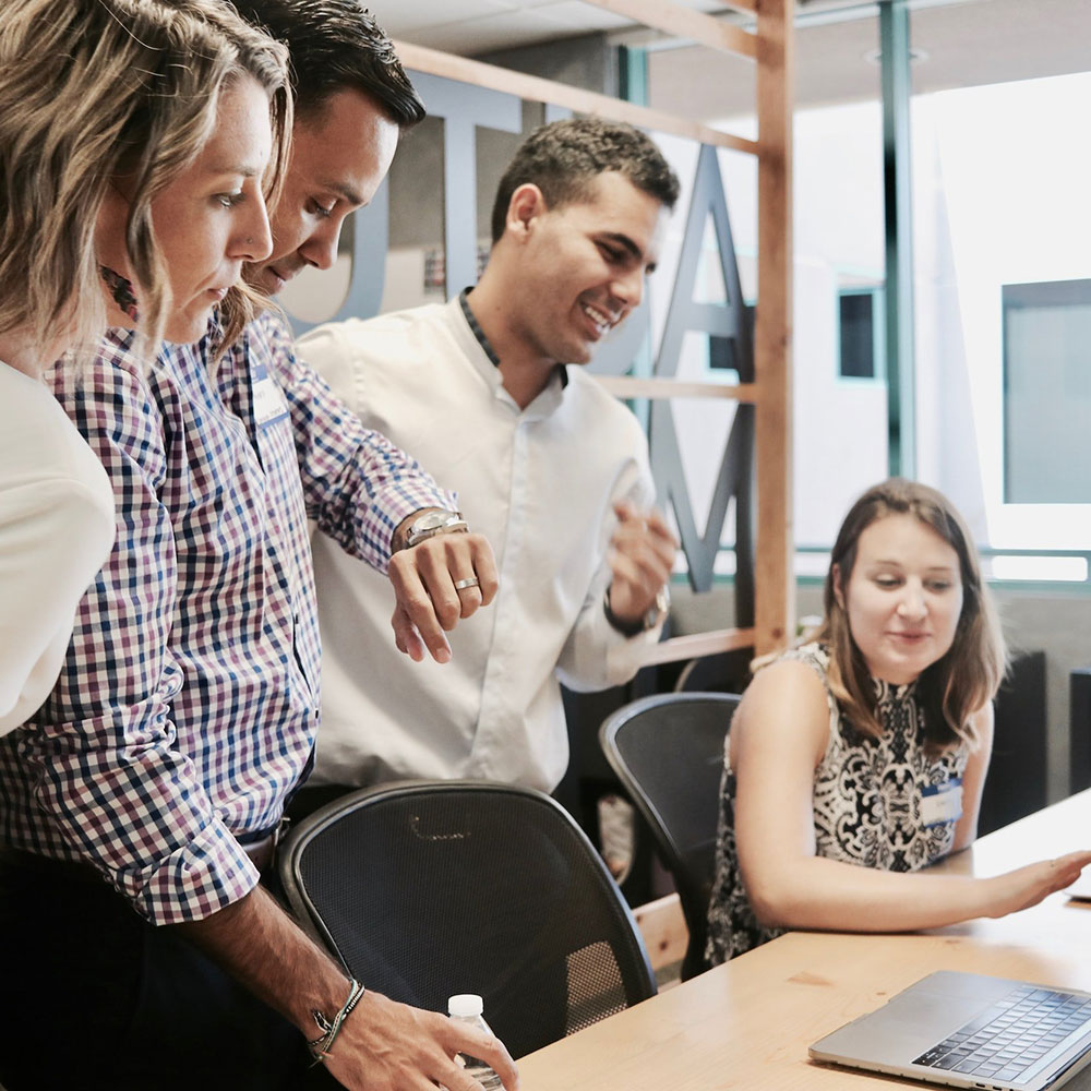 Group of office workers looking at a laptop