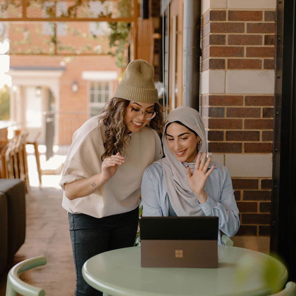 Two women sitting at a table with a laptop.