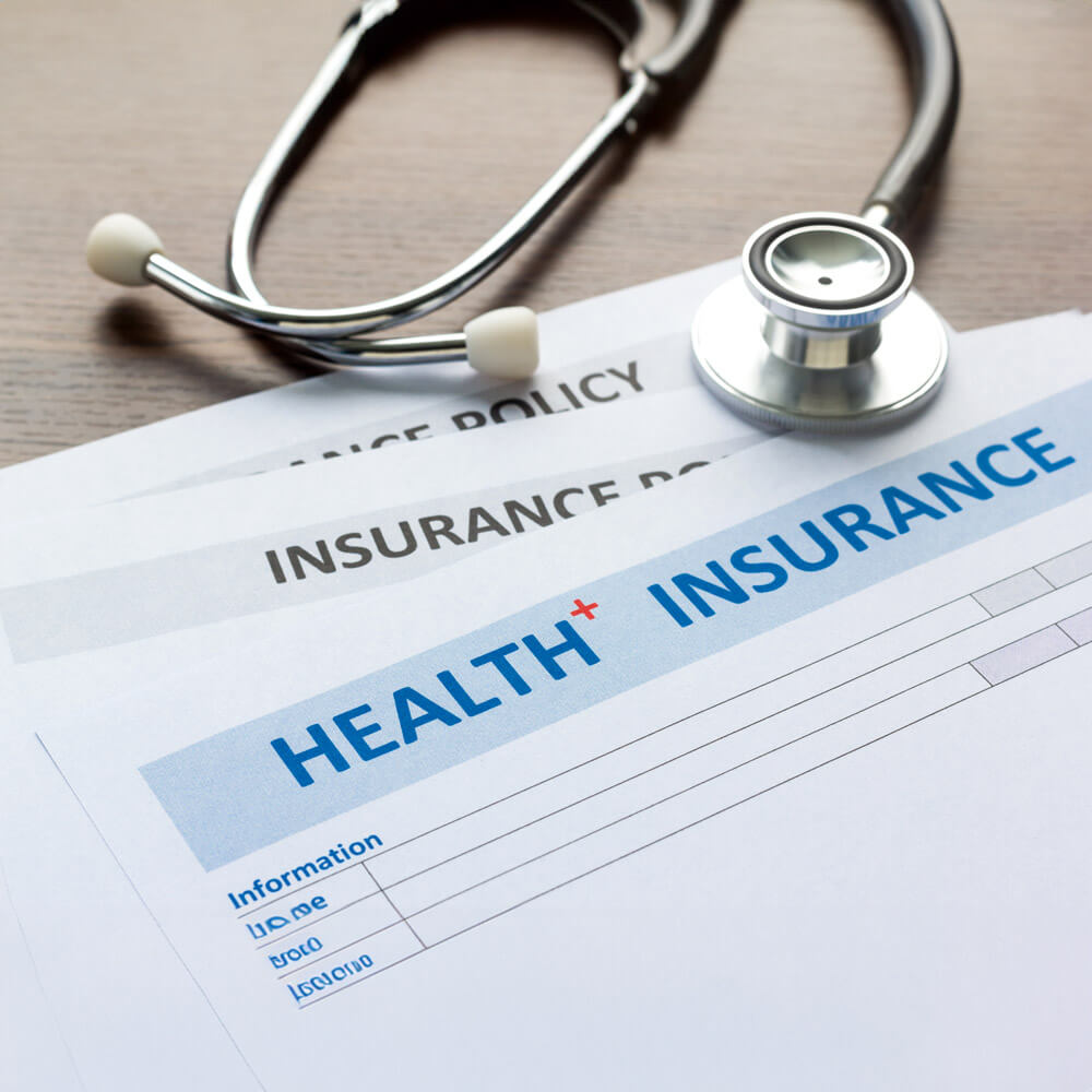 A stethoscope and health insurance documents are placed on a table.